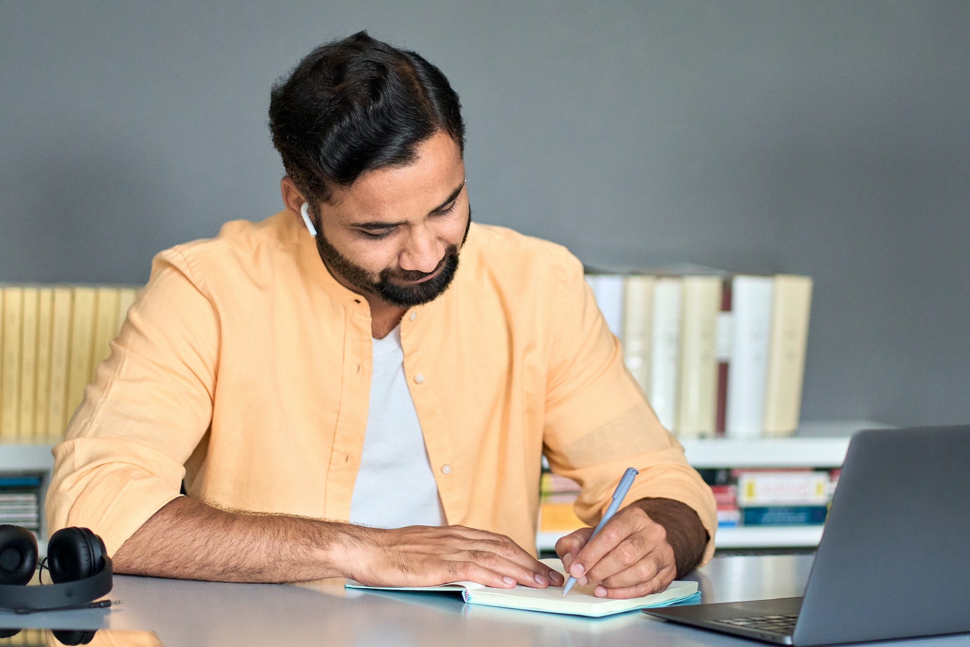 Indian business man writing notes while elearning online course webinar.