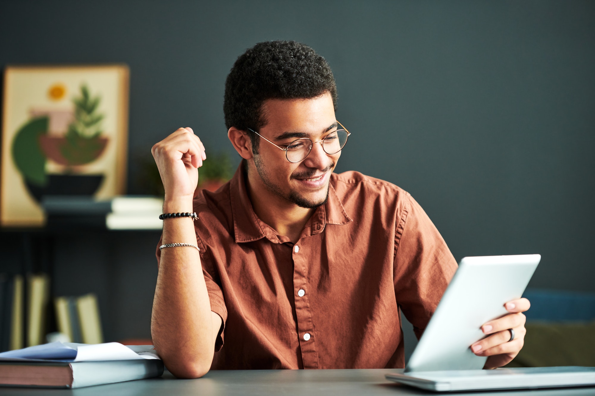 Young smiling student of online course of study looking at tablet screen